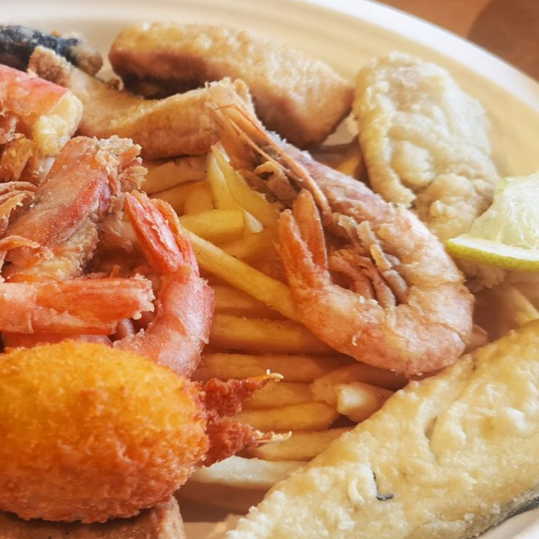 Piatto di frutti di mare con gamberi, pesce fritto e patatine fritte.